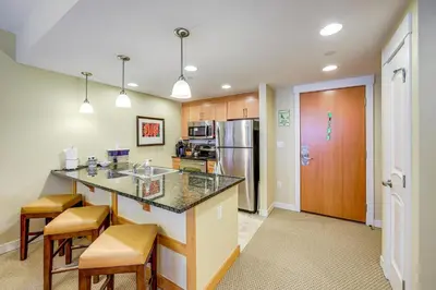 a kitchen with a counter and chairs and a refrigerator at 100 Steps to Gondola Cozy Winter Park Condo! in Winter Park