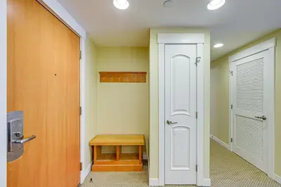 a hallway with a door and a wooden table at 100 Steps to Gondola Cozy Winter Park Condo! in Winter Park