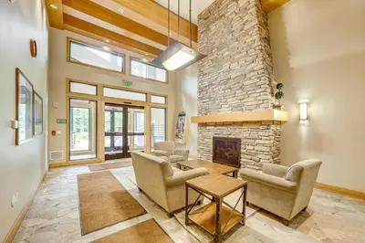 a living room with chairs and a stone fireplace at 100 Steps to Gondola Cozy Winter Park Condo! in Winter Park