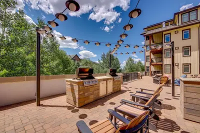 a patio with chairs and a grill on a building at 100 Steps to Gondola Cozy Winter Park Condo! in Winter Park