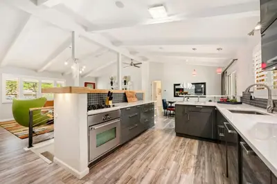 a kitchen with stainless steel appliances and a living room at The Foundry Escape - Hot Tub, Bikes & Game Room in Loveland