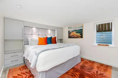 a bedroom with a large bed with orange and blue pillows at Maple Courtyard - Old Town with King Suite & Piano in Fort Collins