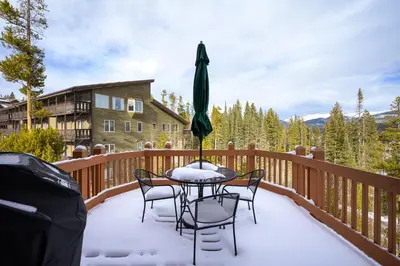a table and chairs on a deck covered in snow at Cloudline Chalet townhouse in Winter Park