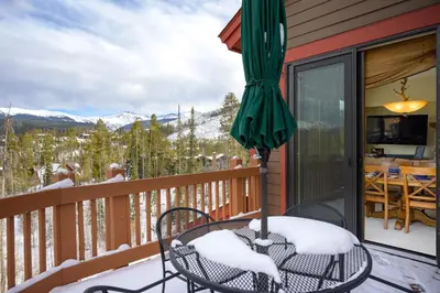 a balcony with a table and chairs and an umbrella at Cloudline Chalet townhouse in Winter Park