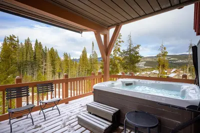 a hot tub on a deck with chairs at Cloudline Chalet townhouse in Winter Park