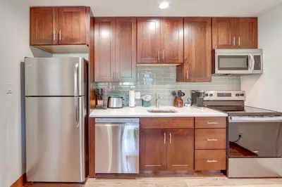 a kitchen with wooden cabinets and a stainless steel refrigerator at Dine, Shop and Shuttle to Resort Winter Park Haven! in Winter Park