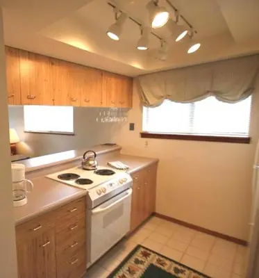 a kitchen with wooden cabinets and a white stove top oven at Our Mountain Blessings Condominium Town Home - peaceful, cozy, and family friendly mountain getaway! The most ideally located unit in Meadow Ridge Resort, in Fraser