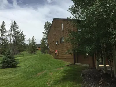 a house with a green yard next to a building at Our Mountain Blessings Condominium Town Home - peaceful, cozy, and family friendly mountain getaway! The most ideally located unit in Meadow Ridge Resort, in Fraser