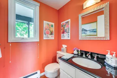 a bathroom with orange walls and a toilet and a sink at Mtn-View Home with Pickleball Court in Louisville! in Louisville