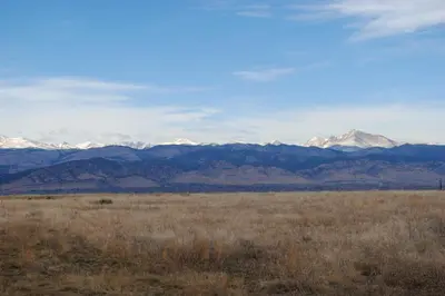 a field with snow covered mountains in the distance at Mtn-View Home with Pickleball Court in Louisville! in Louisville