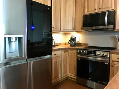 a kitchen with stainless steel appliances and wooden cabinets at Summit Vista Villa- Hike, Ski, Bike! in Fraser
