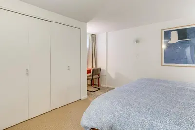 a white bedroom with a bed and a chair at Walkable Apt with Off-Street Parking in Cheesman! in Denver