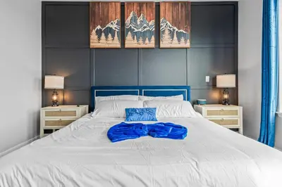 a large white bed with a blue pillow on it at 10 min to DT, Luxe 4BR w Movie Theater, Game Room in Commerce City