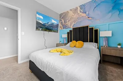 a bedroom with a large bed with yellow pillows at 10 min to DT, Luxe 4BR w Movie Theater, Game Room in Commerce City