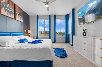 a bedroom with a large bed with blue accents at 10 min to DT, Luxe 4BR w Movie Theater, Game Room in Commerce City