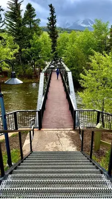 a person walking across a bridge over a river at Luxury modern, Central Ski, No stairs, EV! in Silverthorne