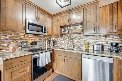 a kitchen with wooden cabinets and stainless steel appliances at 2 Mi to CU Boulder Mtn-View Condo with Pool Access in Boulder
