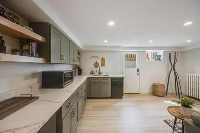 a large kitchen with green cabinets and a table at Cozy Garden Suite by Sloan's Lake and Tennyson! in Wheat Ridge