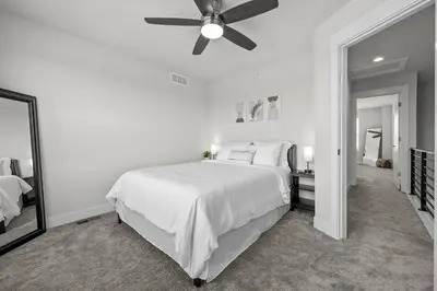 a white bedroom with a bed and a ceiling fan at 3534 W 63rd Ave in Denver