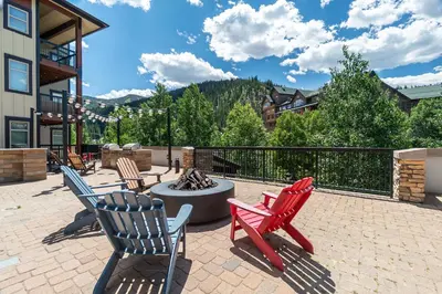 a patio with three chairs and a fire pit at Platinum Top Floor Ski-in Ski-out WP Resort in Winter Park