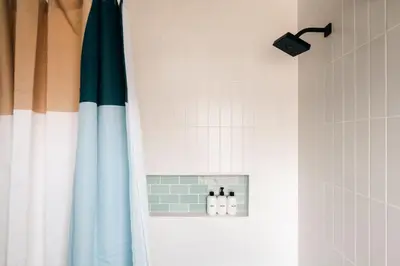 a bathroom with a shower with a blue and white curtain at Colorful Sunnyside Escape - Walk to Dining & Parks in Denver