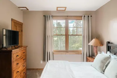 a bedroom with a bed and a television and a window at Ski Hike Relax - Log Cabin with Views - Hot tub in Silverthorne