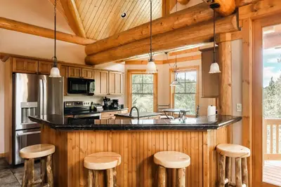 a kitchen with wooden cabinets and a counter with bar stools at Ski Hike Relax - Log Cabin with Views - Hot tub in Silverthorne
