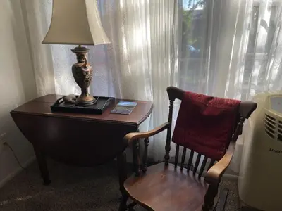 a table with a lamp and a chair next to a window at Sunny and Spacious, Hottub, Piano, Guitars, Fenced Yard, Pets Welcome, LGBT Friendly in Westminster