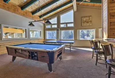 a pool room with two tables and chairs and windows at Ski and Adventure Base Mtn-View Silverthorne Condo in Silverthorne