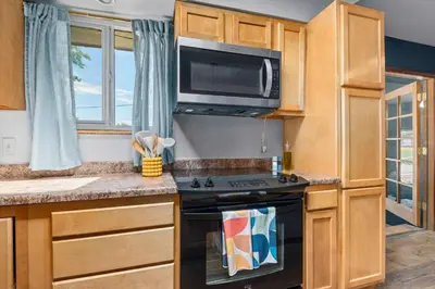 a kitchen with a stove and a microwave at 6BR Family Retreat with Games Billiards Mini Golf BBQ and Yard in Westminster