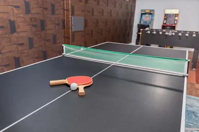 a ping pong table with a red paddle on it at 6BR Family Retreat with Games Billiards Mini Golf BBQ and Yard in Westminster