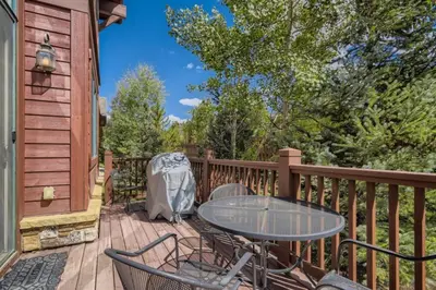 a patio with a table and chairs on a deck at Highland Greens 42 in Breckenridge