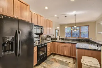a kitchen with wooden cabinets and a black refrigerator at Highland Greens 42 in Breckenridge