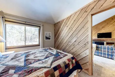 a bedroom with a bed and a wooden wall at Flying Dutchman 1202 in Keystone