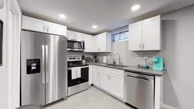 a kitchen with white cabinets and a stainless steel refrigerator at Unique Family Home in Denver in Denver