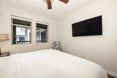 a white bedroom with a bed and a flat screen tv at Premium Unit 4663 - One Bedroom withFull Kitchen - Fraser Crossing Founders Pointe condo in Winter Park