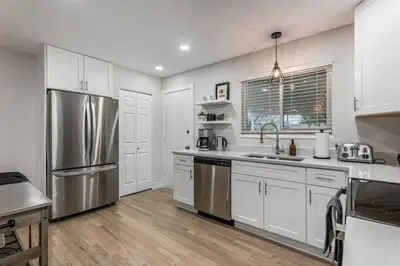 a kitchen with white cabinets and a stainless steel refrigerator at Mile Hi Basecamp Hot tub and Game Room in Denver