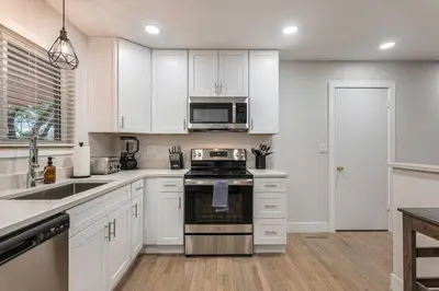 a kitchen with white cabinets and a stove top oven at Mile Hi Basecamp Hot tub and Game Room in Denver