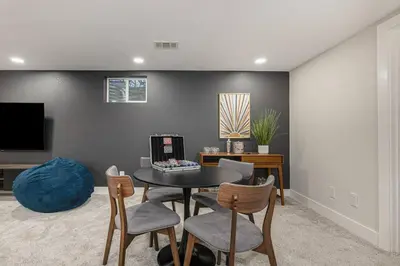 a living room with a table and chairs and a tv at Mile Hi Basecamp Hot tub and Game Room in Denver