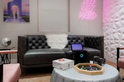 a living room with a black leather couch and a table at Good Vibe Tribe-2 Mi DT-Hot Tub-K Bed-Pet Friendly in Denver