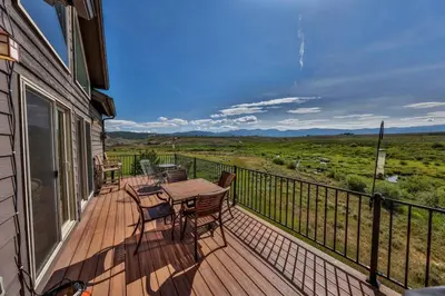 a wooden deck with a table and chairs on it at Mountain Bliss 3 BR Retreat With Views and Hot Tub in Tabernash