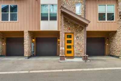 a building with three garage doors and a yellow door at 2 Mi to Fraser River Trail Townhome with Hot Tub! in Fraser