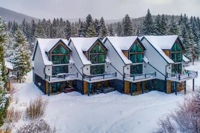 a house covered in snow with trees in the background at Ski-InandSki-Out Gemini Lift Access! Home with Hot Tub in Winter Park