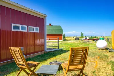 two chairs and a table next to a barn at Yak Ranch with Mountain Views, Near Wellington!