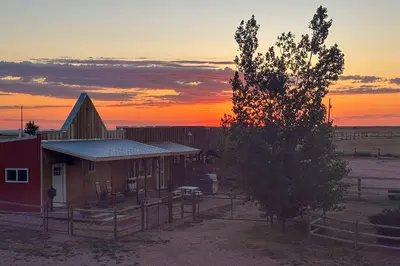 a barn with a tree in front of a sunset at Yak Ranch with Mountain Views, Near Wellington!