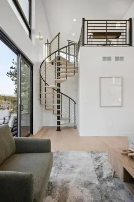 a spiral staircase in a living room with a couch at Modern Mtn Escape! Hot Tub Fireplace Views! in Bailey