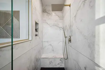 a bathroom with a shower with white marble walls at Modern Mtn Escape! Hot Tub Fireplace Views! in Bailey