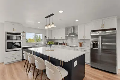 a kitchen with white cabinets and a large kitchen island with chairs at Lake Arbor Family Retreat with Backyard Oasis in Arvada