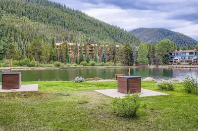 two benches sitting on the grass next to a lake at 1702 The Willows condo in Keystone