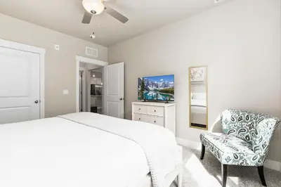 a white bedroom with a bed and a chair at Northfield Old Town Flat with Attached Garage and EV in Fort Collins